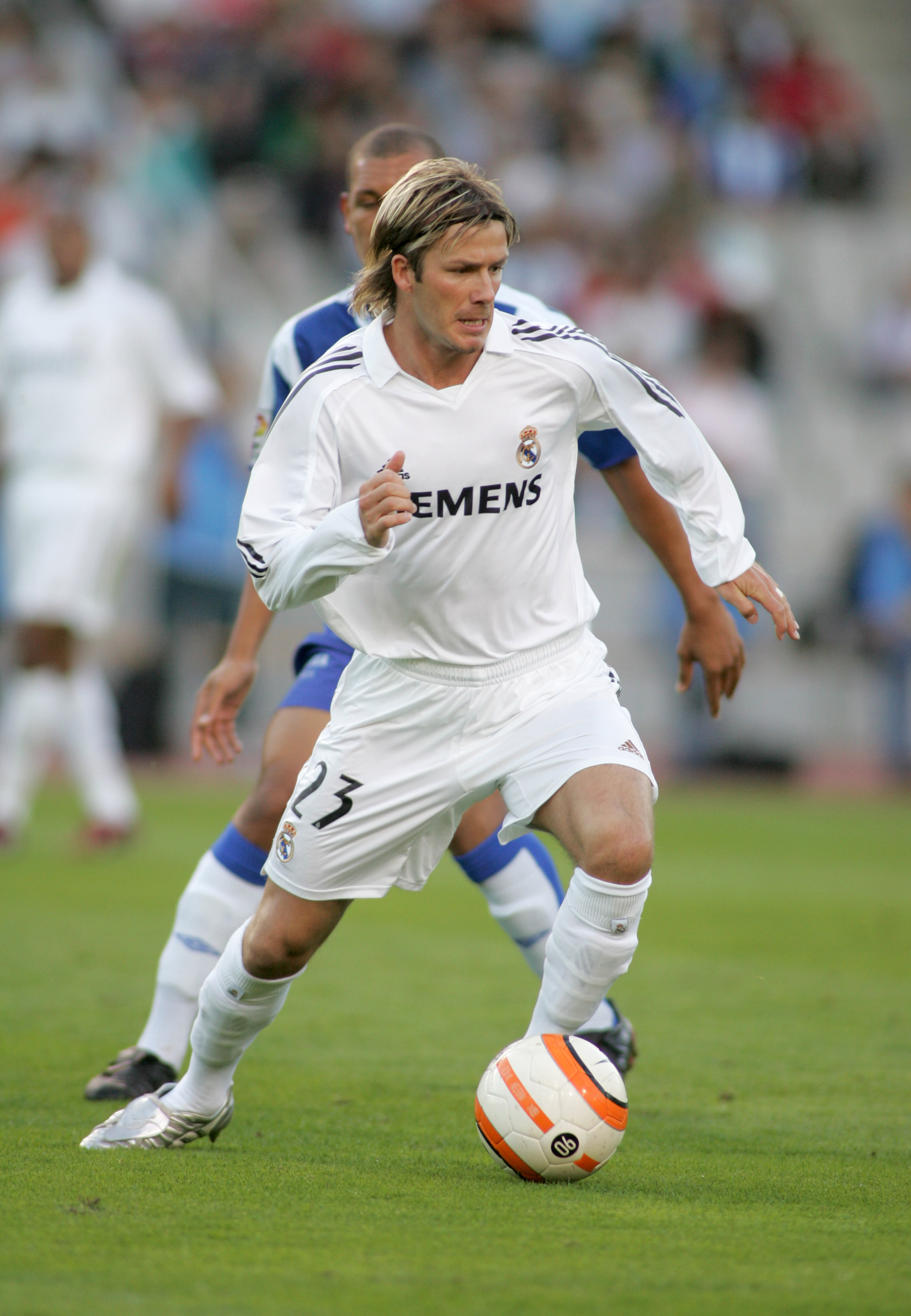 Futbolista con camiseta blanca conduciendo el balón durante un partido en post de requisitos ley beckham