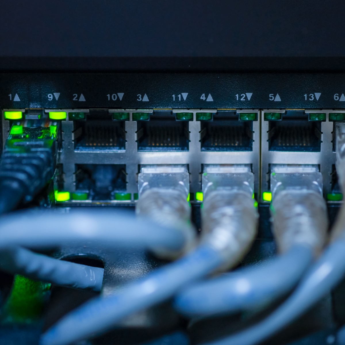 Conmutador Ethernet con varios puertos RJ45 y luces LED verdes indicando tráfico de datos en un rack de comunicaciones gigabit en cumplimiento con la Ley Europea de Infraestructura de Gigabit.