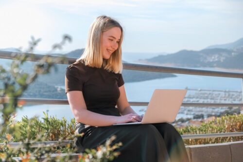 Persona trabajando con un portátil en una terraza con vistas al mar