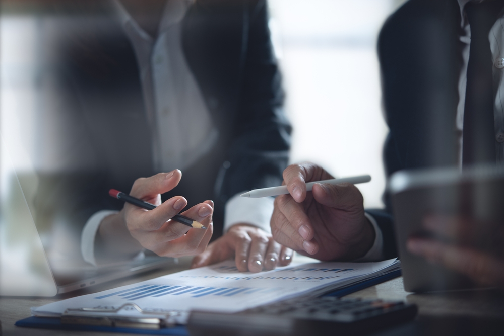 Manos de profesionales revisando gráficos financieros para un plan de negocio de emprendedores