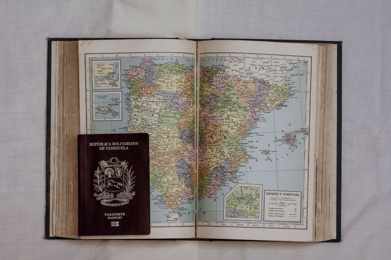 Documentación y llegada a España tras la concesión Pasaporte venezolano sobre un atlas de España y Portugal: trámites tras la residencia de emprendedores concedida